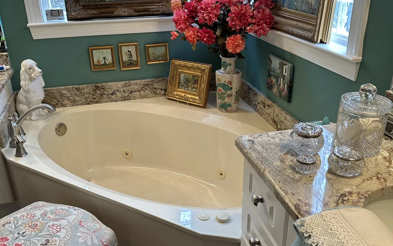 A renovated master bathroom inside a Birmingham Metro Area home, showing a tiled walk-in shower, updated double vanity, and warm overhead lighting. The finish work reflects the classic architectural character common to homes in this area of Alabama.